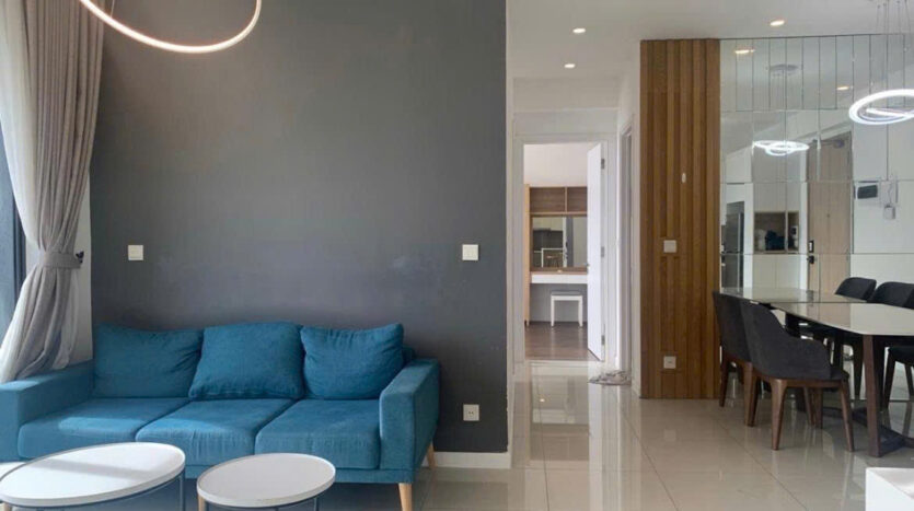 Living and dining area of 89sqm Estella Heights apartment with teal sofa, marble dining table and gold pendant lights