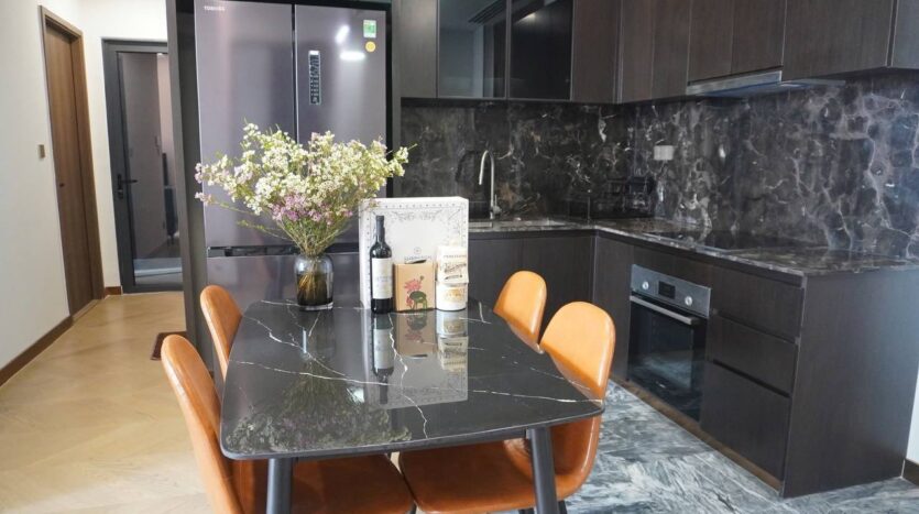 Bếp và bàn ăn marble đen căn hộ Lumiere Riverside Tháp West với ghế da cam | Kitchen and black marble dining table at Lumiere Riverside West Tower apartment with tan leather chairs