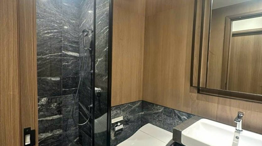 Phòng tắm marble đen và gỗ óc chó với buồng tắm kính căn hộ Lumiere Riverside Tháp West | Bathroom finished in black marble and walnut wood with glass shower at Lumiere Riverside West Tower apartment