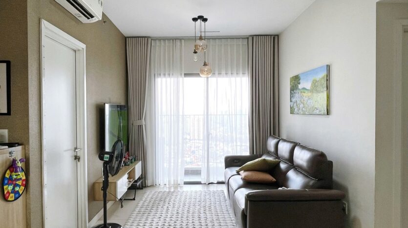 Phòng khách căn hộ Masteri Thảo Điền Tower 5 với sofa da nâu và ban công kính | Living room of Masteri Thao Dien Tower 5 apartment with brown leather sofa and glass balcony