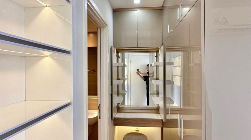 Hành lang vào phòng ngủ căn hộ Masteri Thảo Điền với tủ gloss và walk-in closet | Hallway leading to bedroom of Masteri Thao Dien apartment with gloss cabinets and walk-in closet