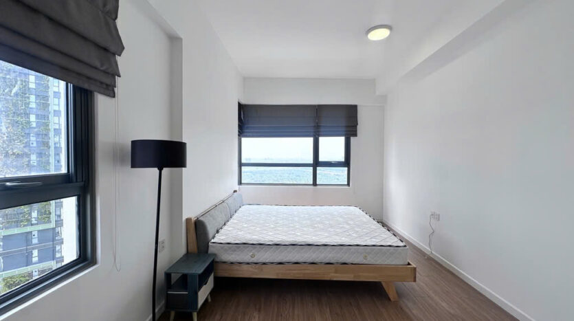 Master bedroom with floor lamp and large window overlooking Saigon River at Masteri An Phu Tower B apartment