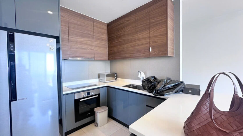 Modern kitchen with walnut cabinets and side-by-side fridge at The Nassim Tower A apartment