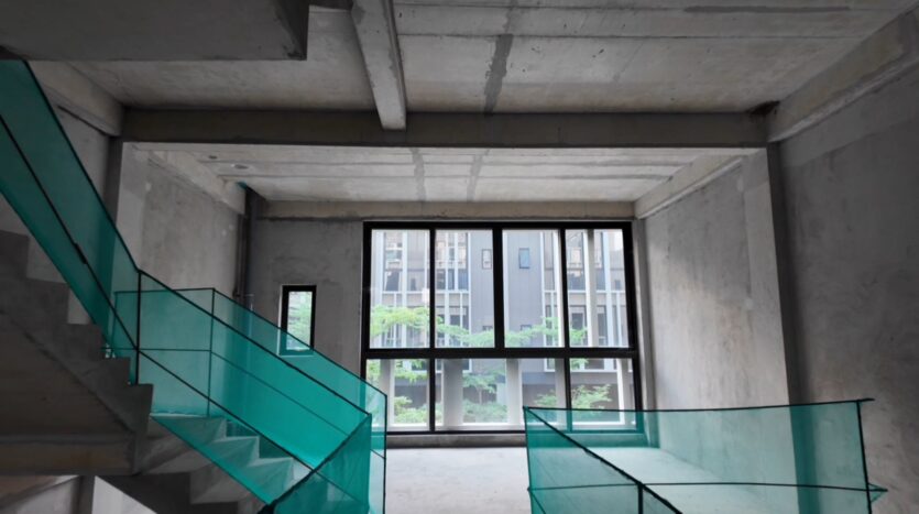 Tầng trên nhà phố The Orchard Sycamore với cửa kính lớn và cầu thang bàn giao thô | Upper floor of The Orchard Sycamore townhouse with large glass windows and raw concrete staircase