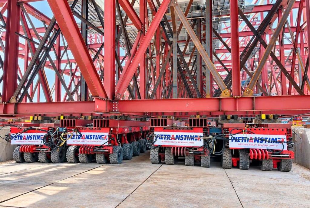 Xe tự hành đa trục SPMT nâng tổ hợp vòm thép cầu đi bộ khi thử tải tháng 10/2026 | SPMT self-propelled transporters lifting the steel arch assembly during the load test, Oct 2026
